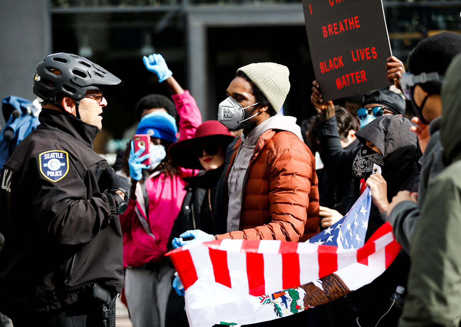 A Seattle police officer stands before a crowd of protesters.